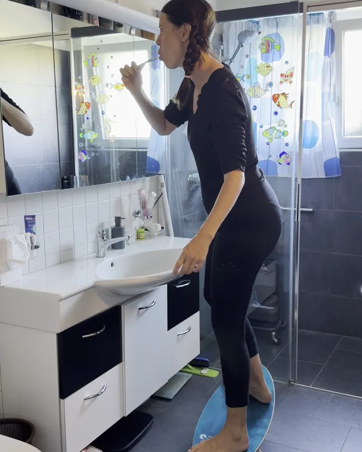 Frau putzt Zähne auf dem Balance Board